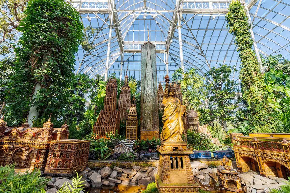 miniature buildings and landmarks of NYC with toy trains in a botanical garden.