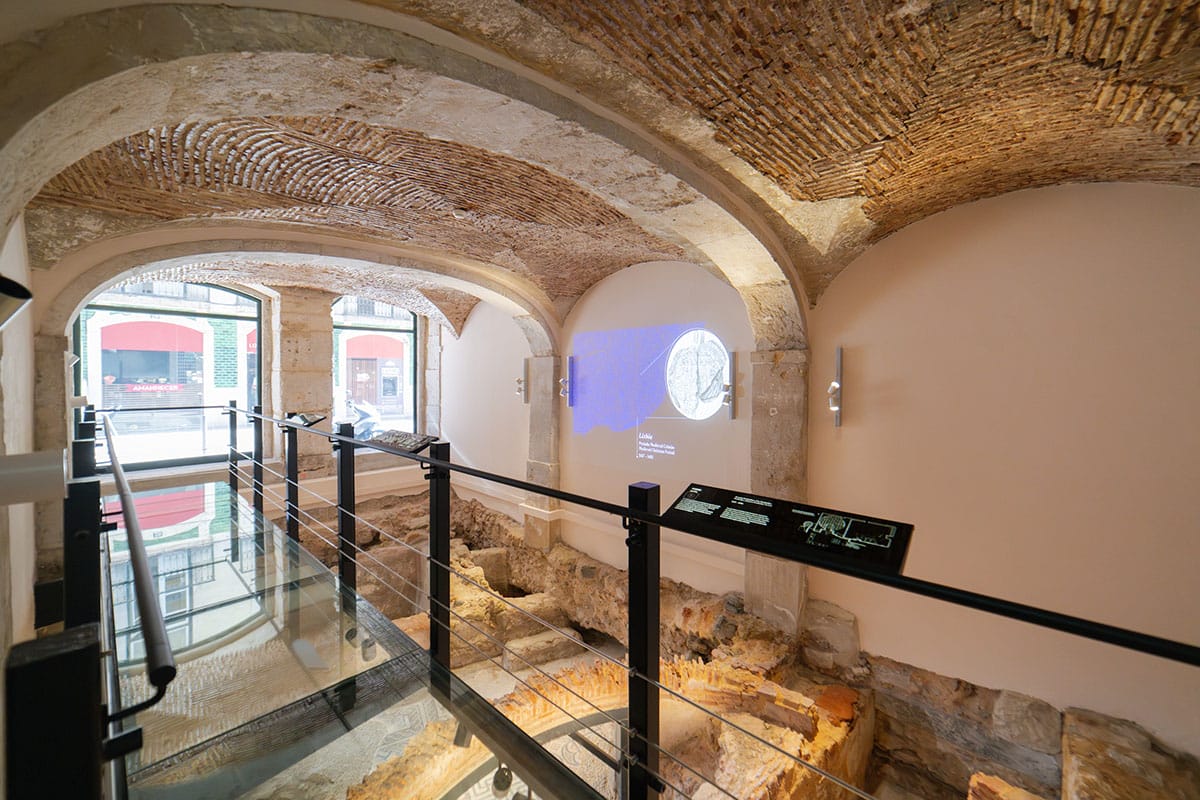 glass-floored exhibit of Roman ruins under a building.