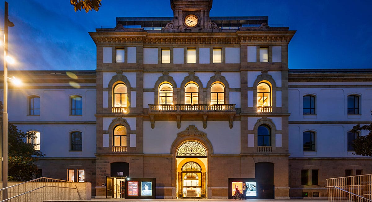 three-story stone hotel at dusk with illuminated windows.