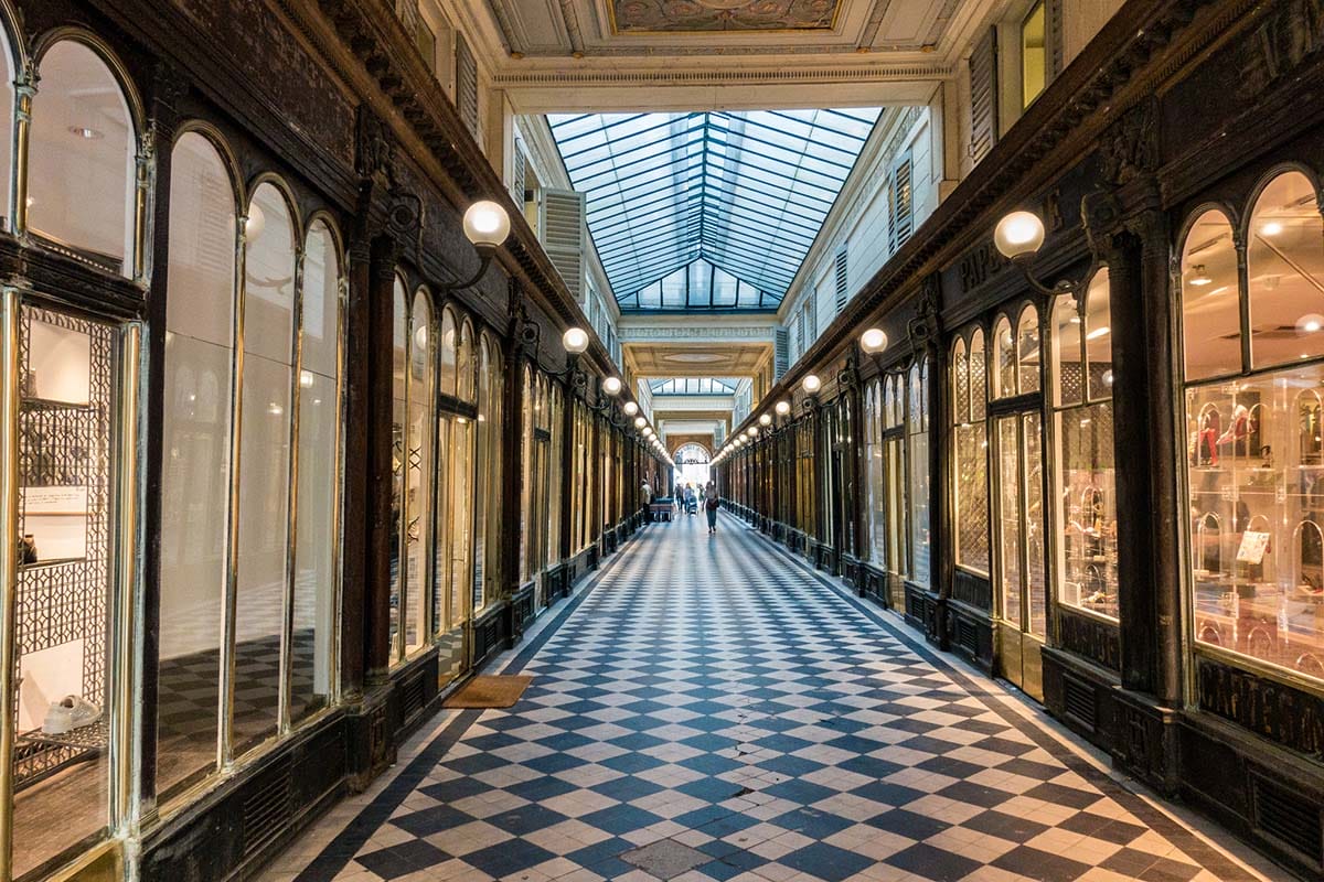 nearly empty Parisian passageway with a checkered tile floor and glass ceiling.