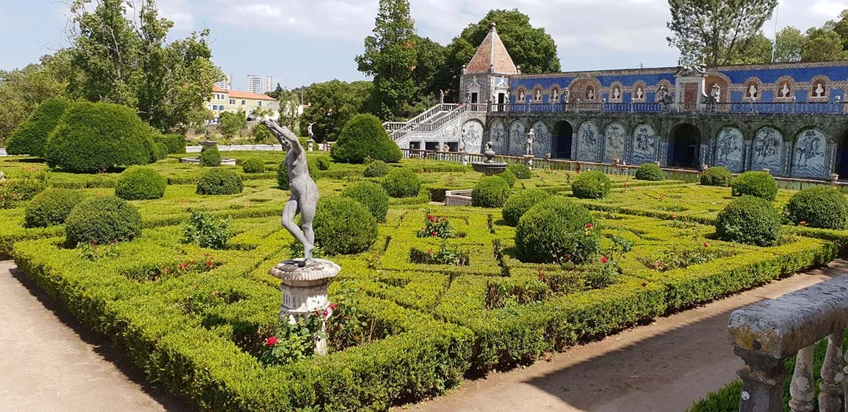 manicured gardens surrounded by a walking path near a historic building.