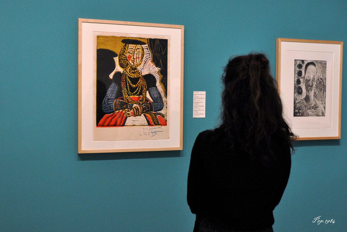 woman looking at Picasso paintings on a blue wall.