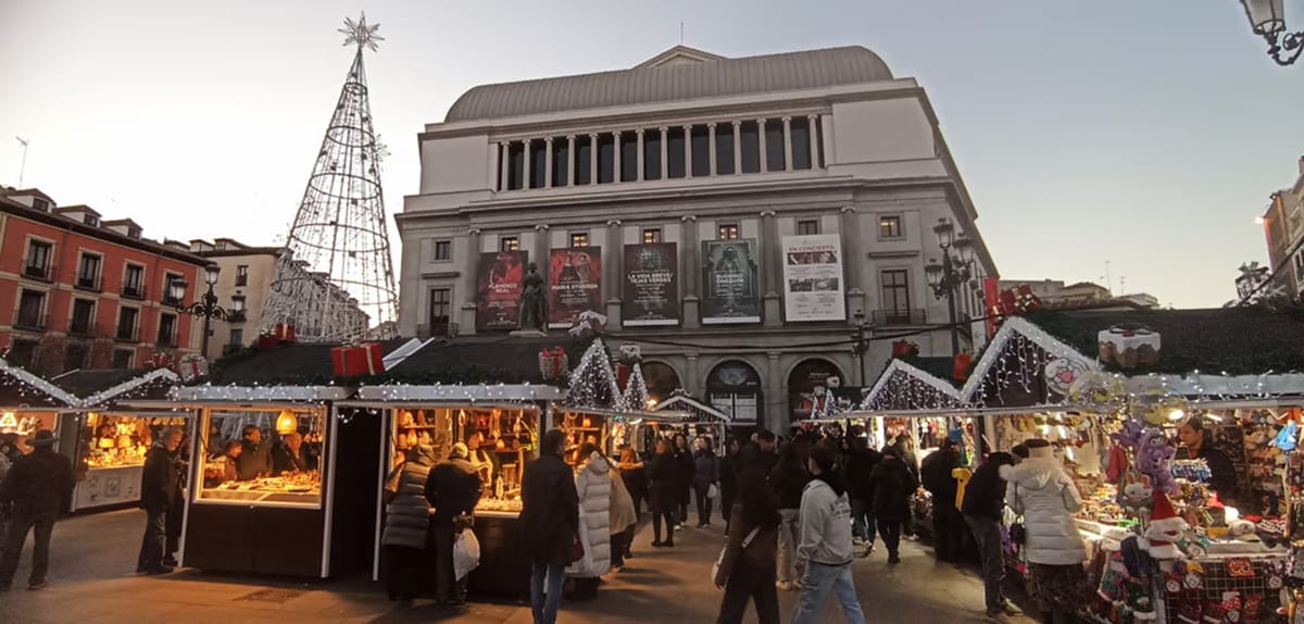 people exploring an outdoor Christmas market at dusk.