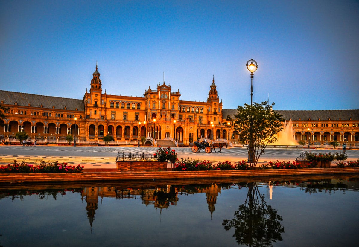 horse-drawn carriage going past a river and historic building at golden hour.