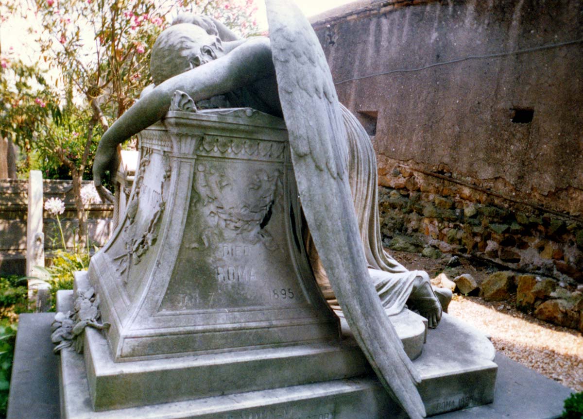stone sculpture of an angel weeping in a cemetery.
