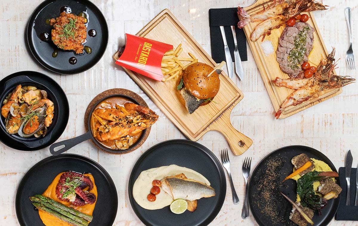 black plates of seafood on a white table.