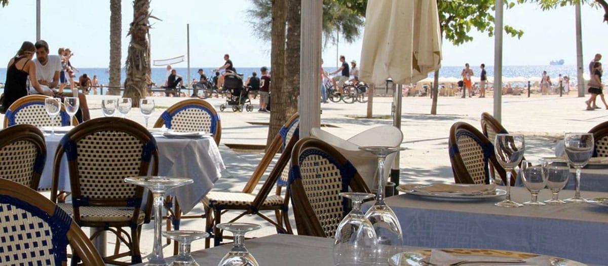 covered tables with rattan chairs overlooking the seashore.
