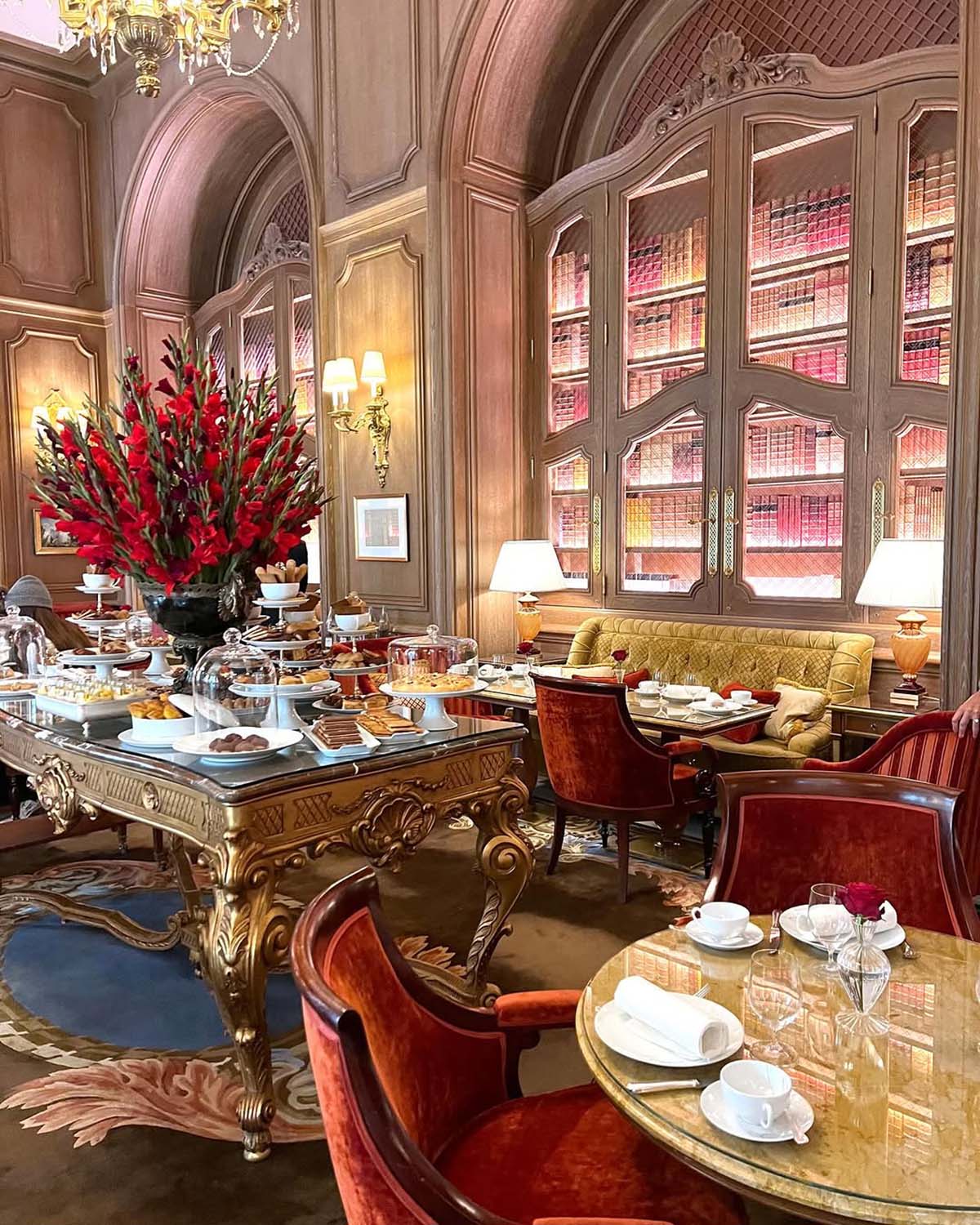 opulent hotel dining room with illuminated bookcases and ornate tables and chairs.