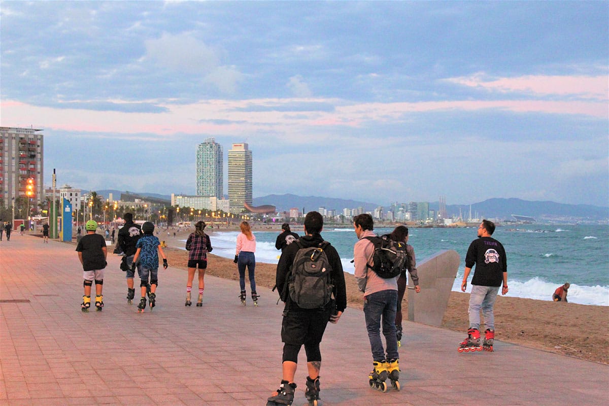 people roller blading on a sidewalk near the beach in Barcelona.
