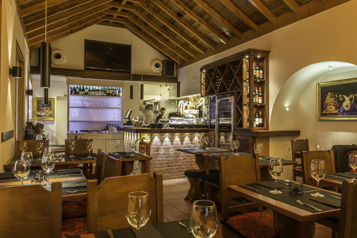 tables and chairs in a restaurant with exposed beams and a brick counter.