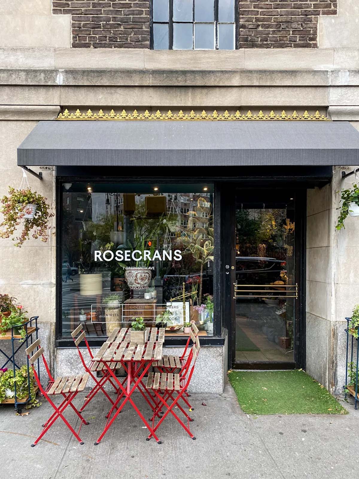tables and chairs outside of a glass-windowed floral shop and cafe.