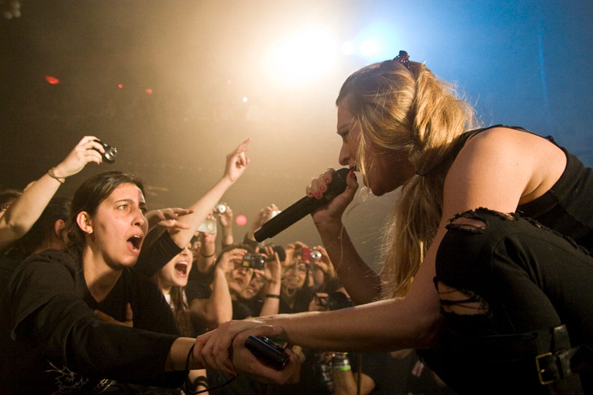 performer singing into a microphone near a group of fans.