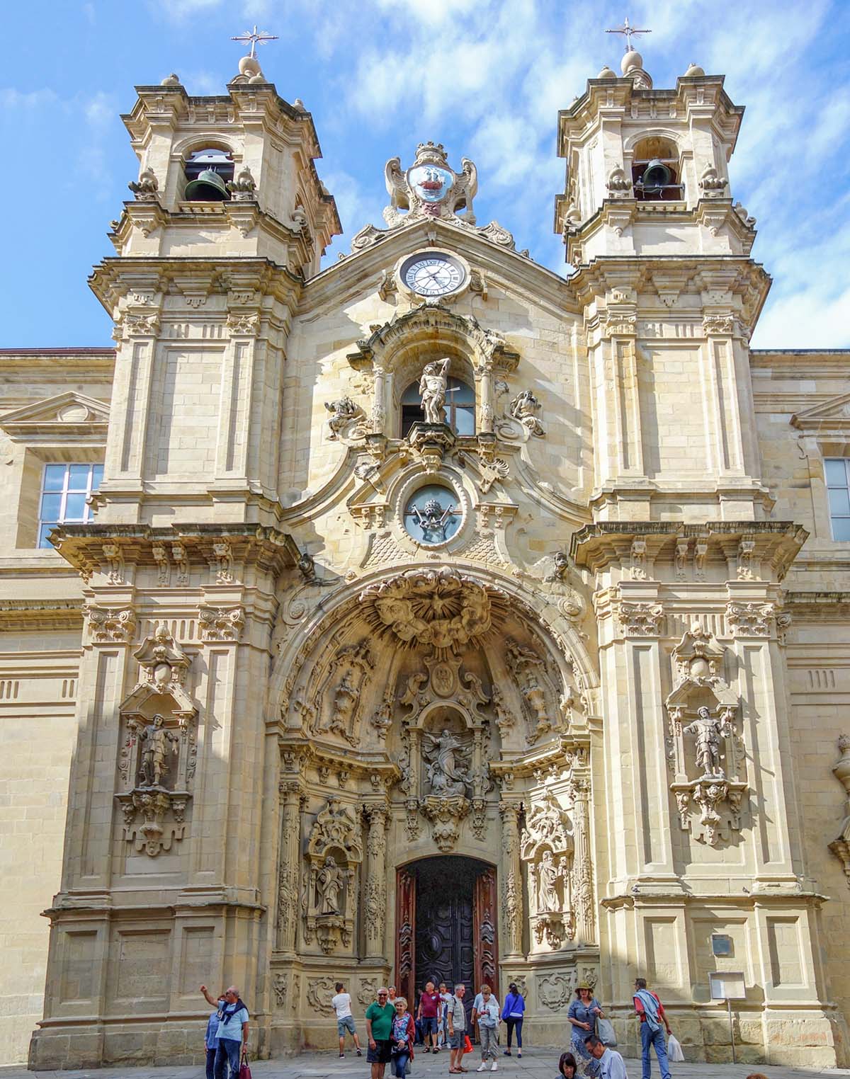 ornate arched entryway into a stone basilica under a blue sky.