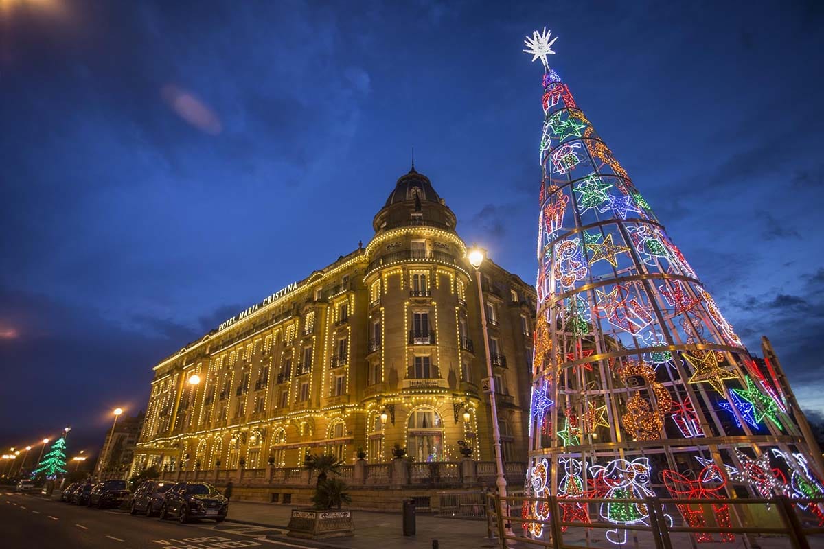large hotel lit with Christmas lights beside a wire Christmas tree.
