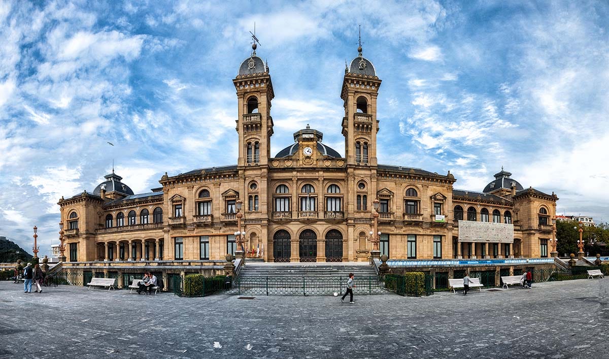 three-story ornate building with two tall towers in the center and three domes.