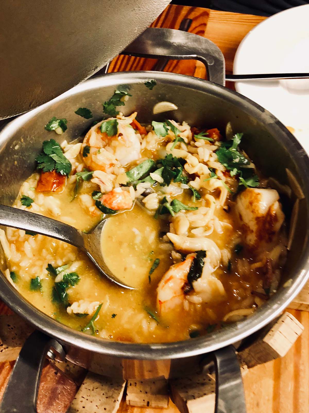 pot filled with seafood and rice with a serving spoon.