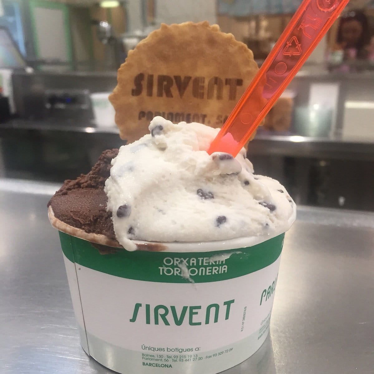 small bowl of chocolate and vanilla ice cream with a pink spoon and a small wafer.