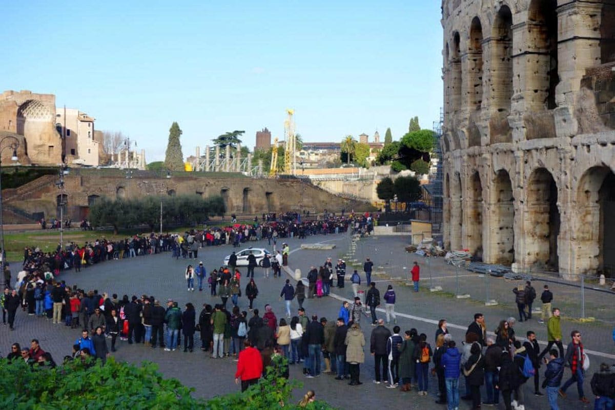 long lines of people waiting outside of the Coliseum in Rome.