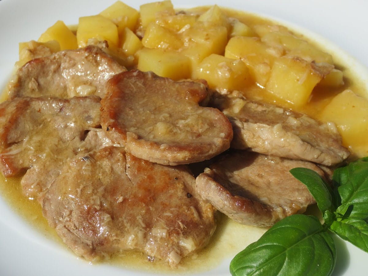 white plate of pork with whisky sauce and potatoes.