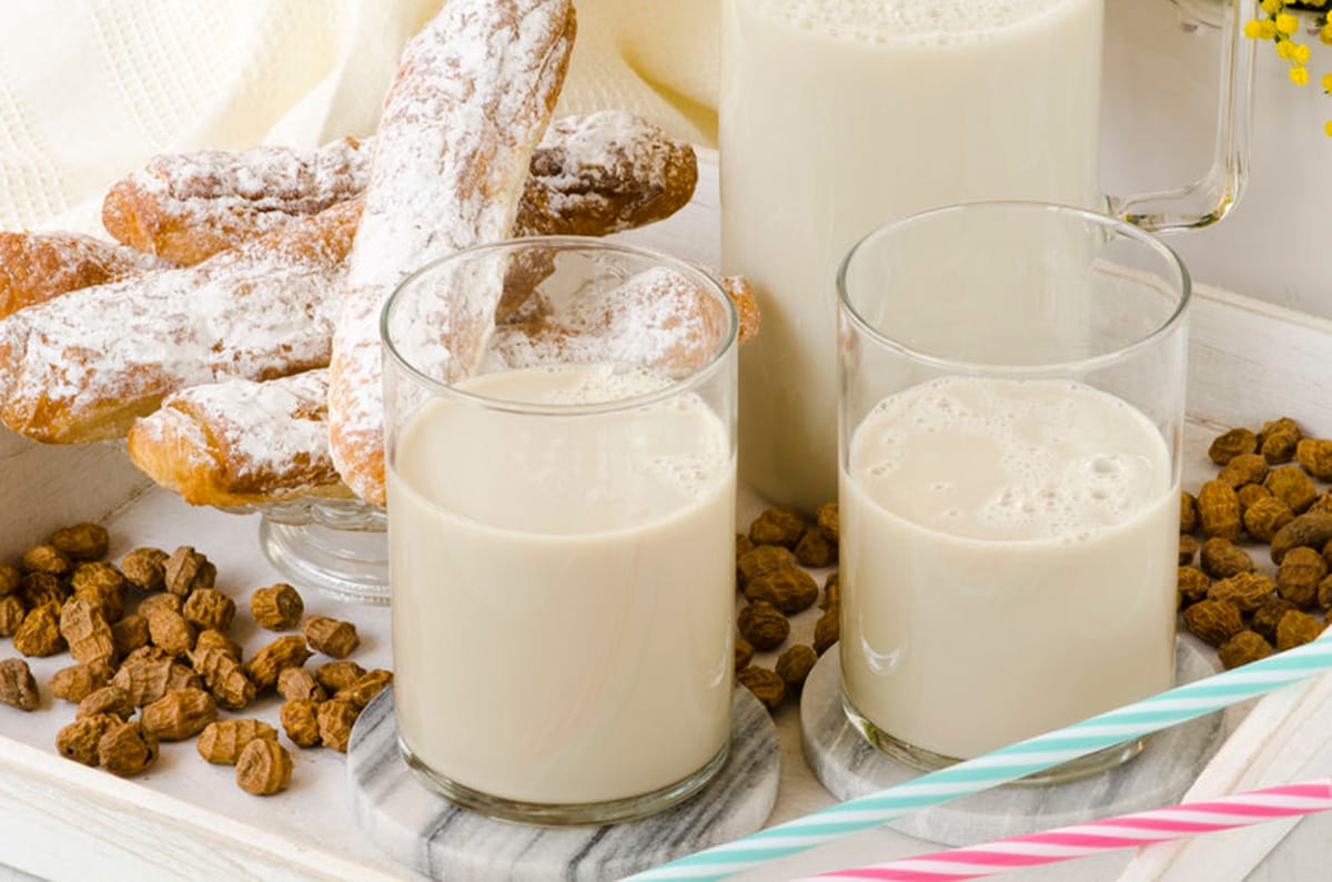 two glasses of horchata with fartons on a platter.