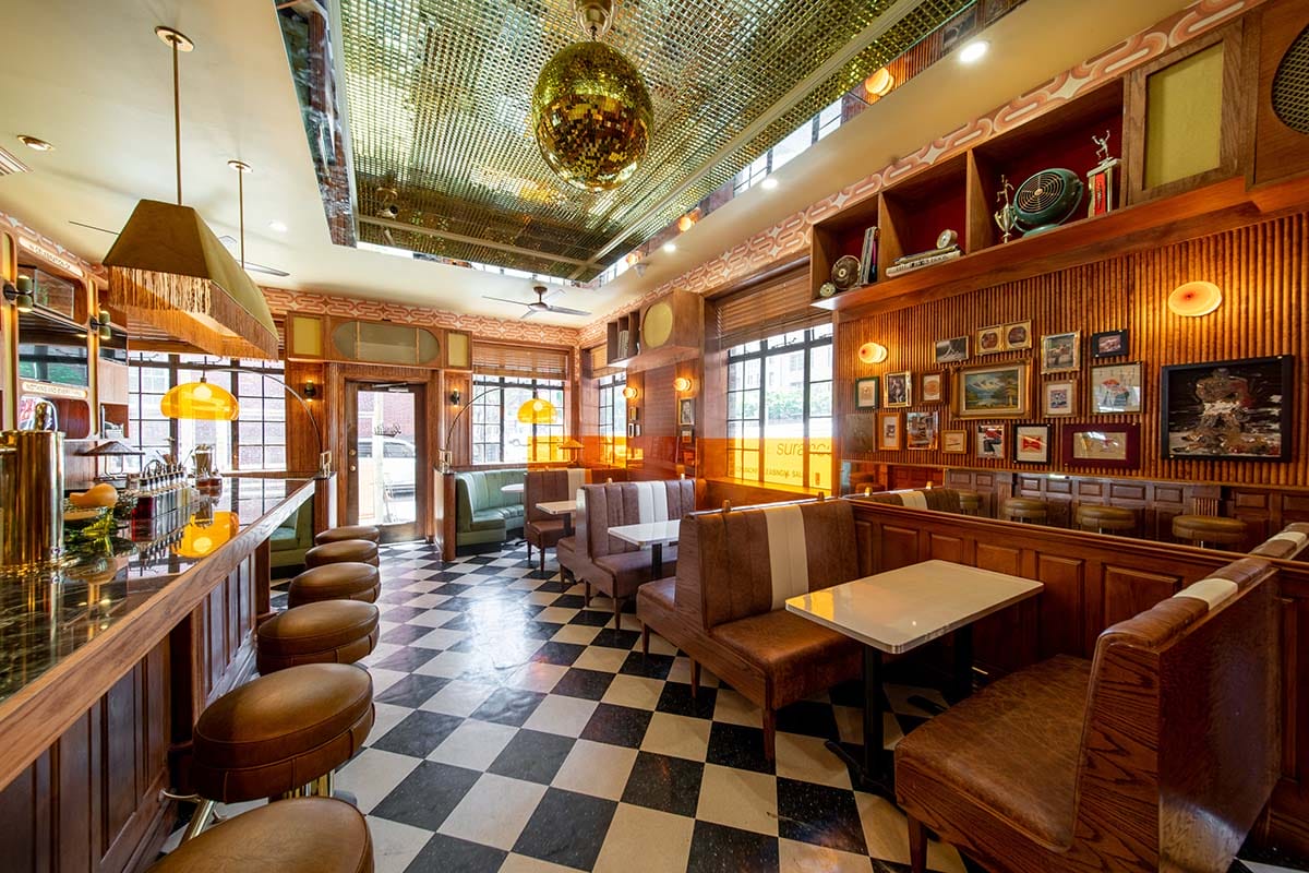 leather-seated booths with a long bar with stools with wood-paneled walls and a disco ball hanging from the ceiling.