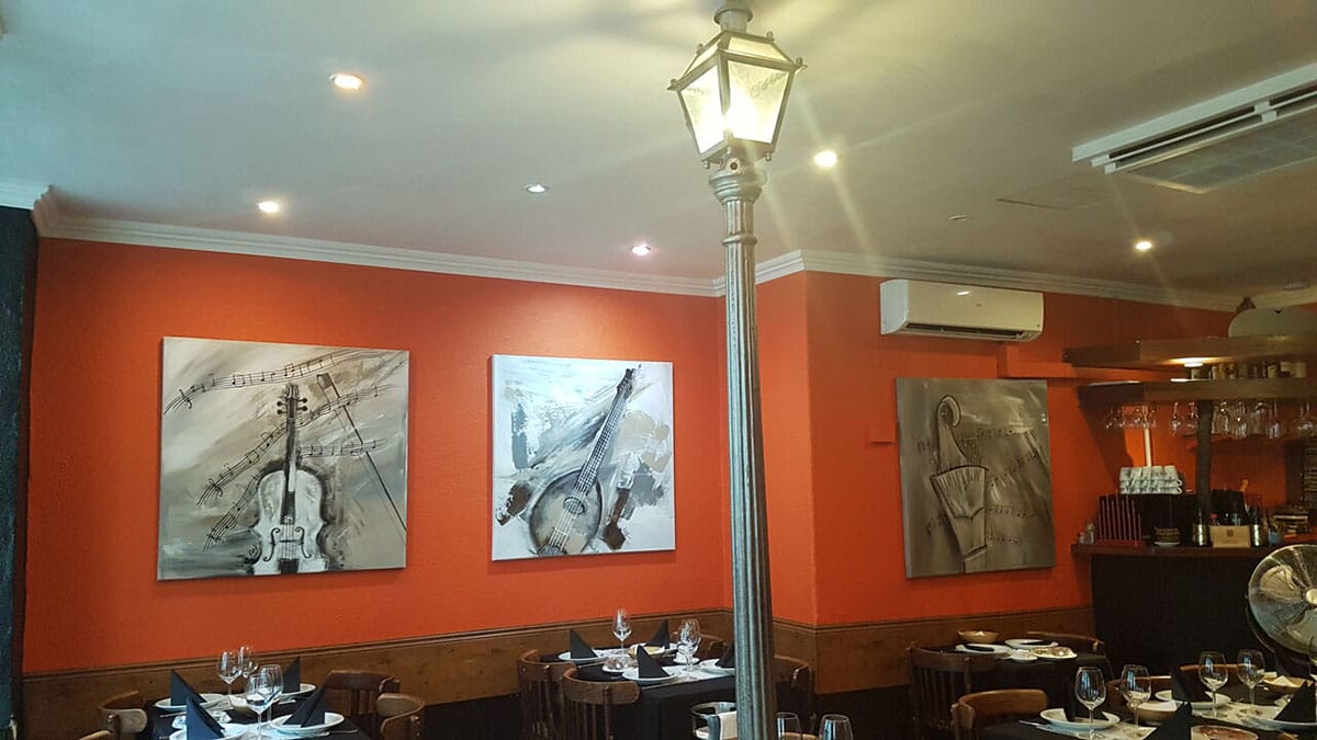 restaurant with red walls, black and white musical paintings on the wall, and a lamppost in the center of the room.