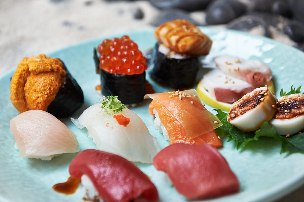 blue ceramic plate of colorful different sushi pieces.