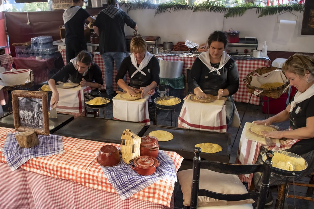 four ladies making corn tortillas in a booth.