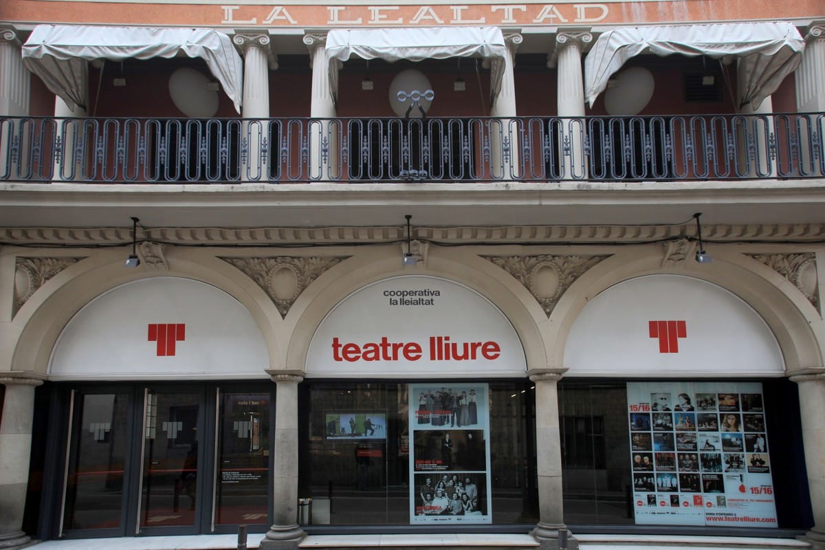 entrance to a theater with a balcony and large arched windows.