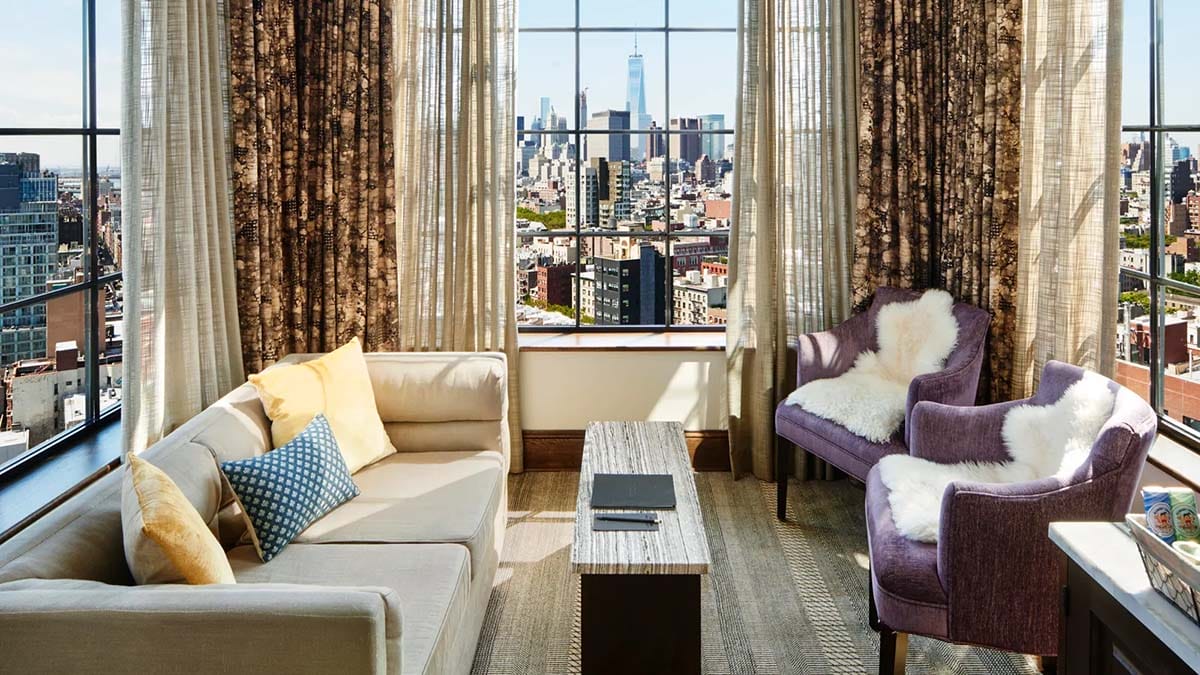 couches and chairs in a room with large picture windows overlooking the NYC skyline.