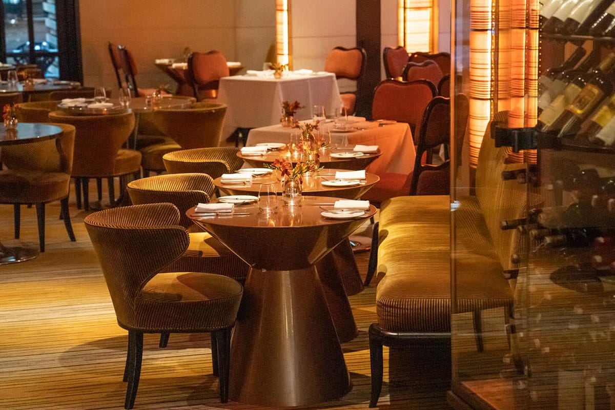 modern tables and chairs inside of a warmly lit restaurant.