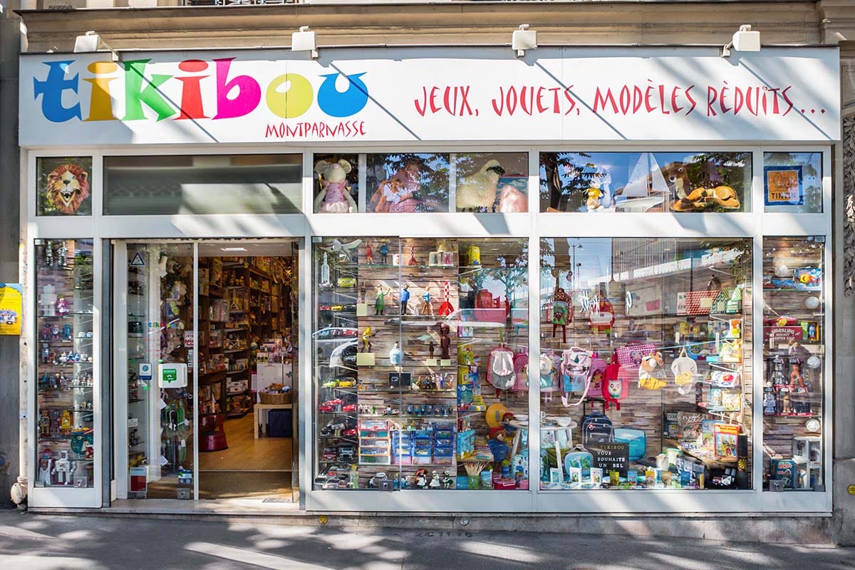 toys lined up on glass shelves in a shop with large windows overlooking the street.