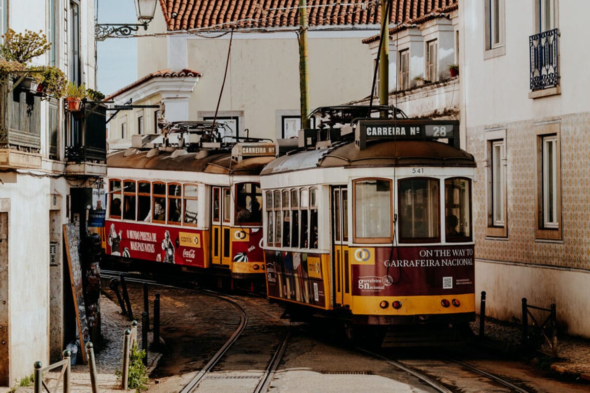 two yellow trams on a narrow street in Lisbon.