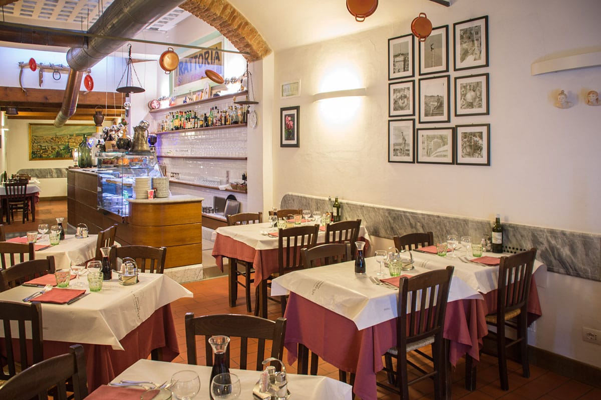 tables with white and pink tablecloths inside a small restaurant.