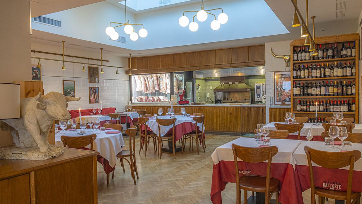 sunlit dining room with red and white covered tables and wooden chairs.