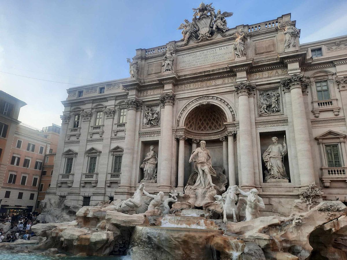 view of the Trevi Fountain with a large historic building in the background.