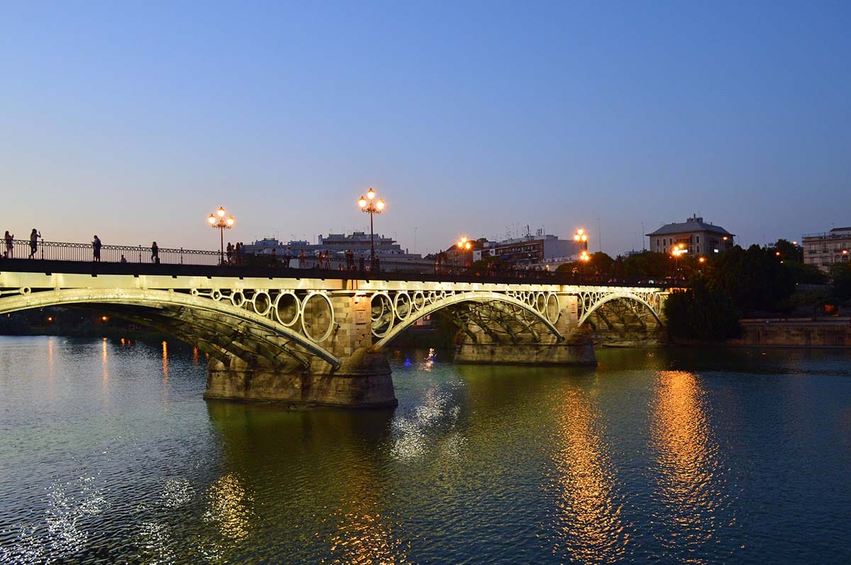 illuminated bridge across a river at sunset.