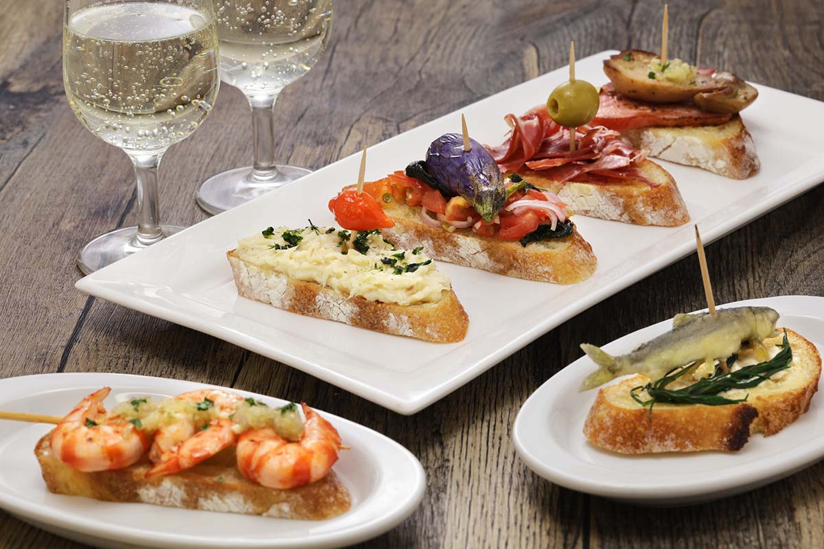 three small plates of pintxos with two glasses of txakoli.