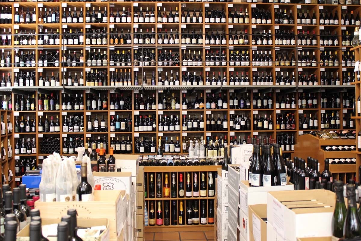 a wall of wooden shelves with hundreds of wine bottles.