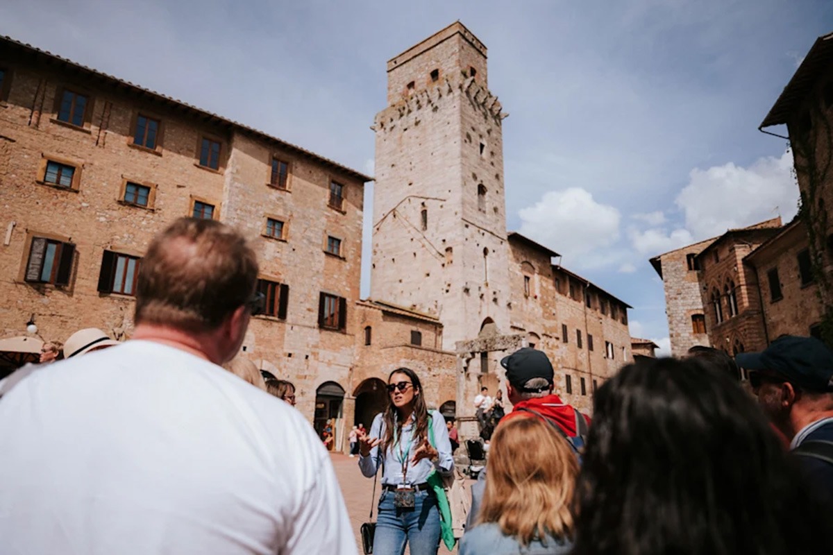 tour guide leading a small group of people through a historic Tuscan village.