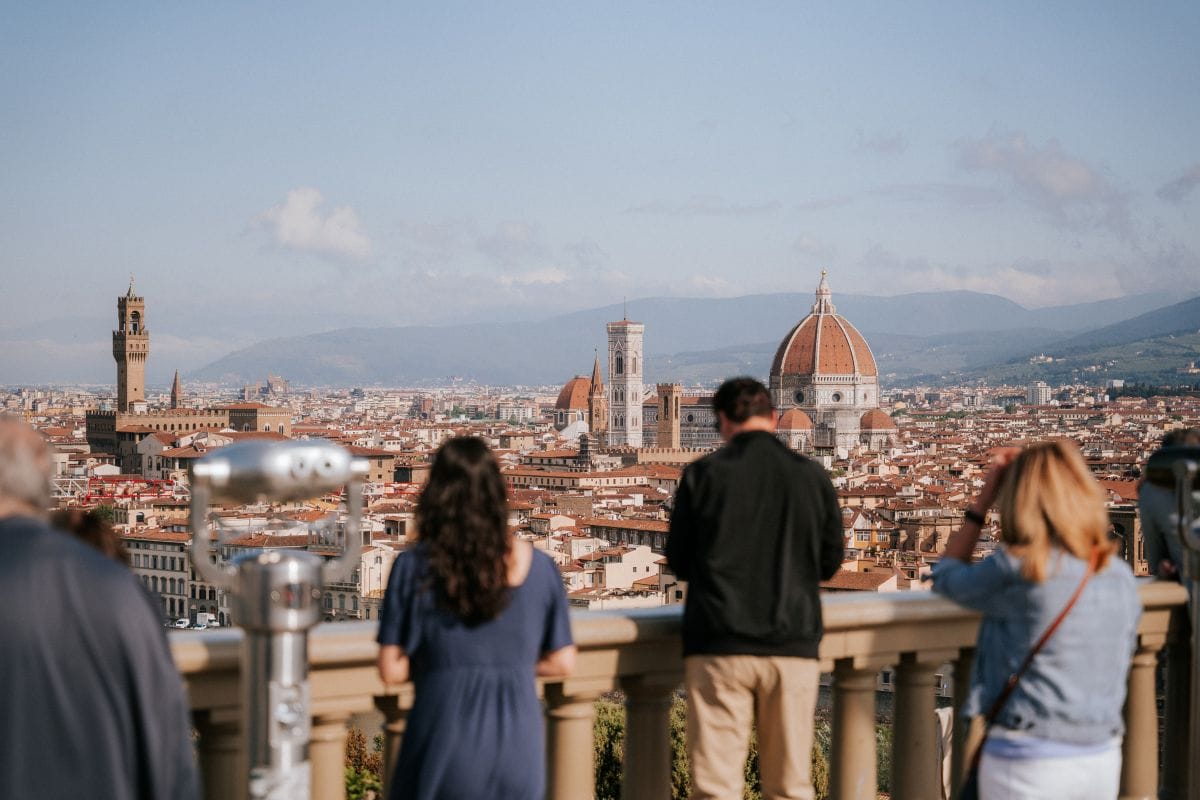 A group of people at a view point looking at Florence in the summer.