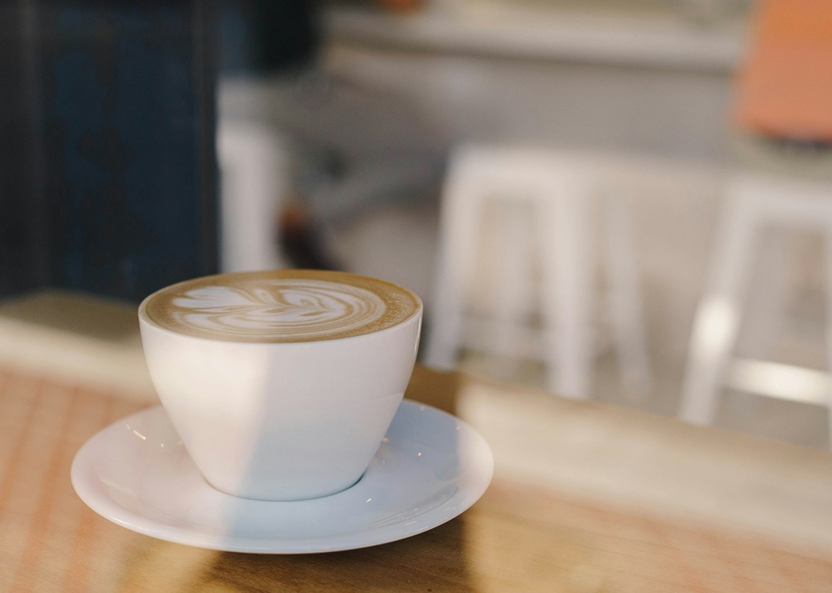 large cappuccino in a white mug on a white saucer.