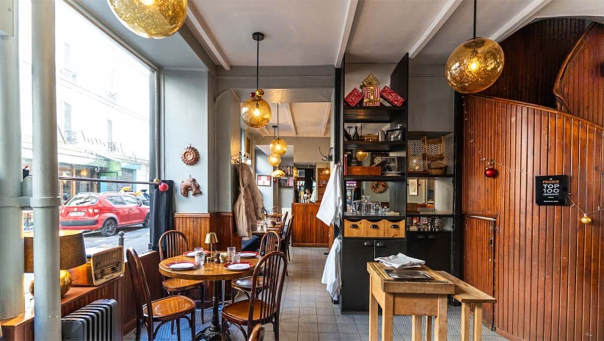 small tables and chairs near large windows inside of a charming modern cafe.