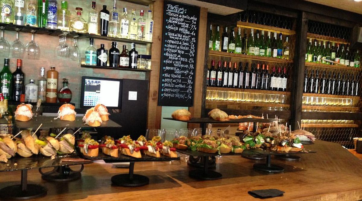 pintxos arranged on stone platters on a wooden bar counter.