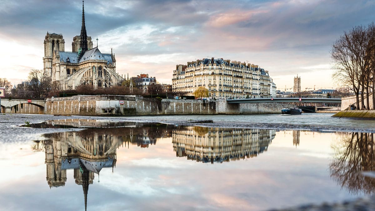 historic buildings on an island in the middle of a river connected to the city with a bridge.