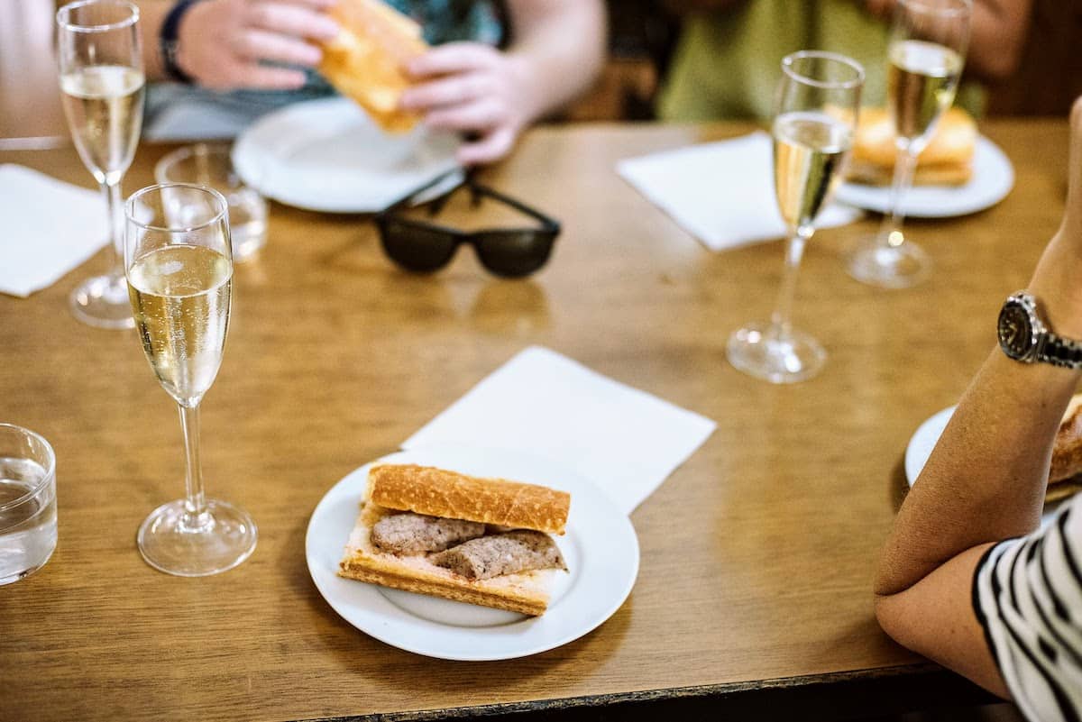 botifarra sandwich on a plate with glasses of cava.