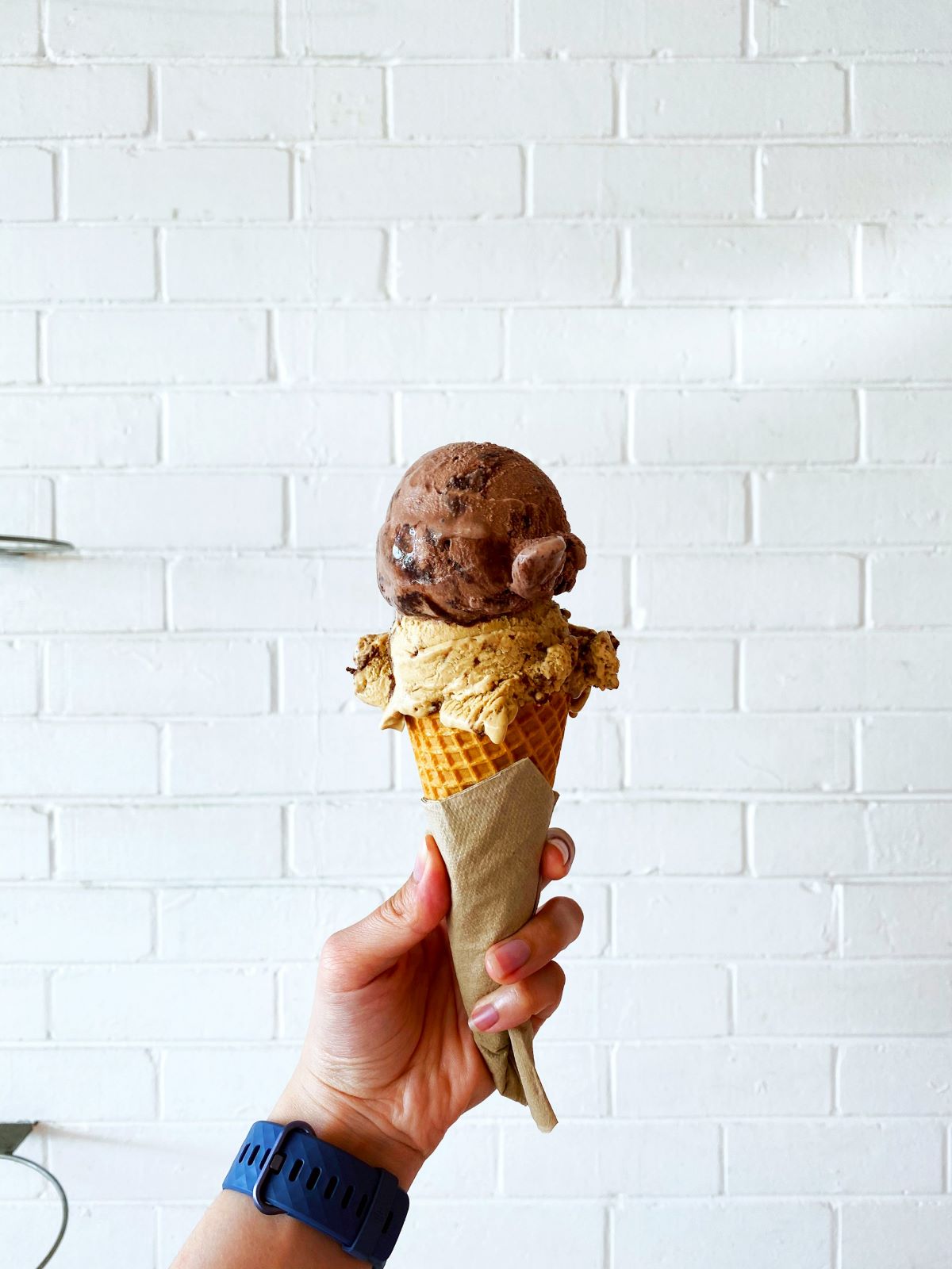 A woman holding homemade ice cream at a local creamery in Boston. Homemade ice cream is one of the Boston famous foods you have to try.