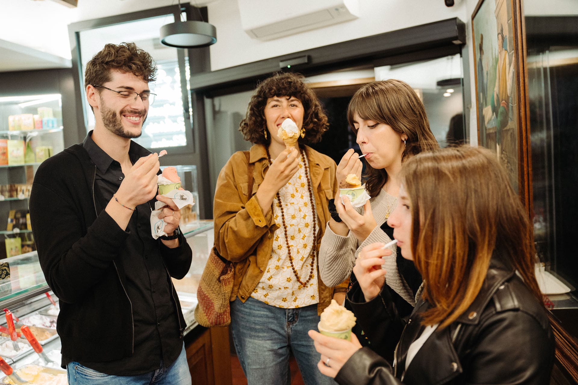 Four friends enjoy colorful scoops of gelato inside a traditional Italian gelateria.