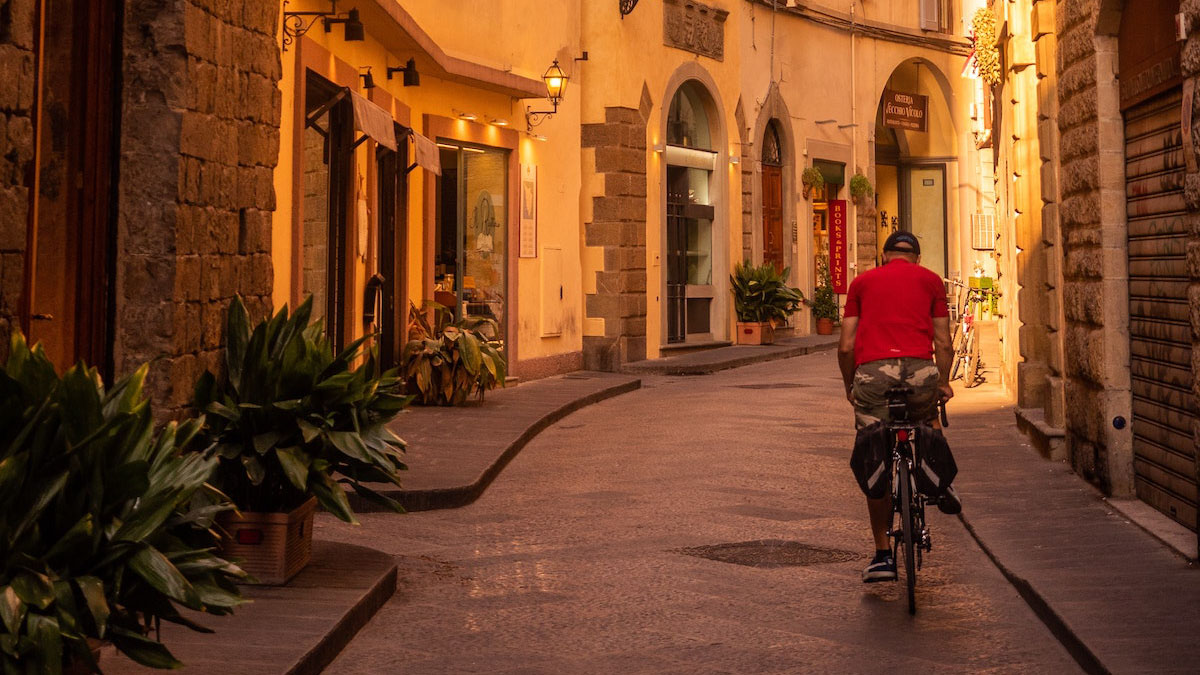 man riding a bicycle down a Florentine street.
