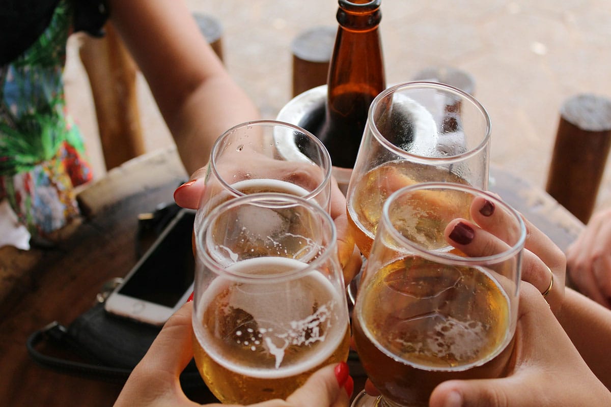 four people toasting with glasses of beer outdoors.